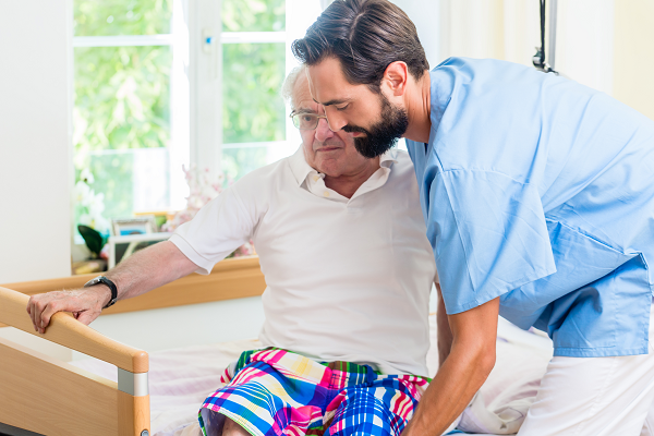 Carer assisting man out of bed