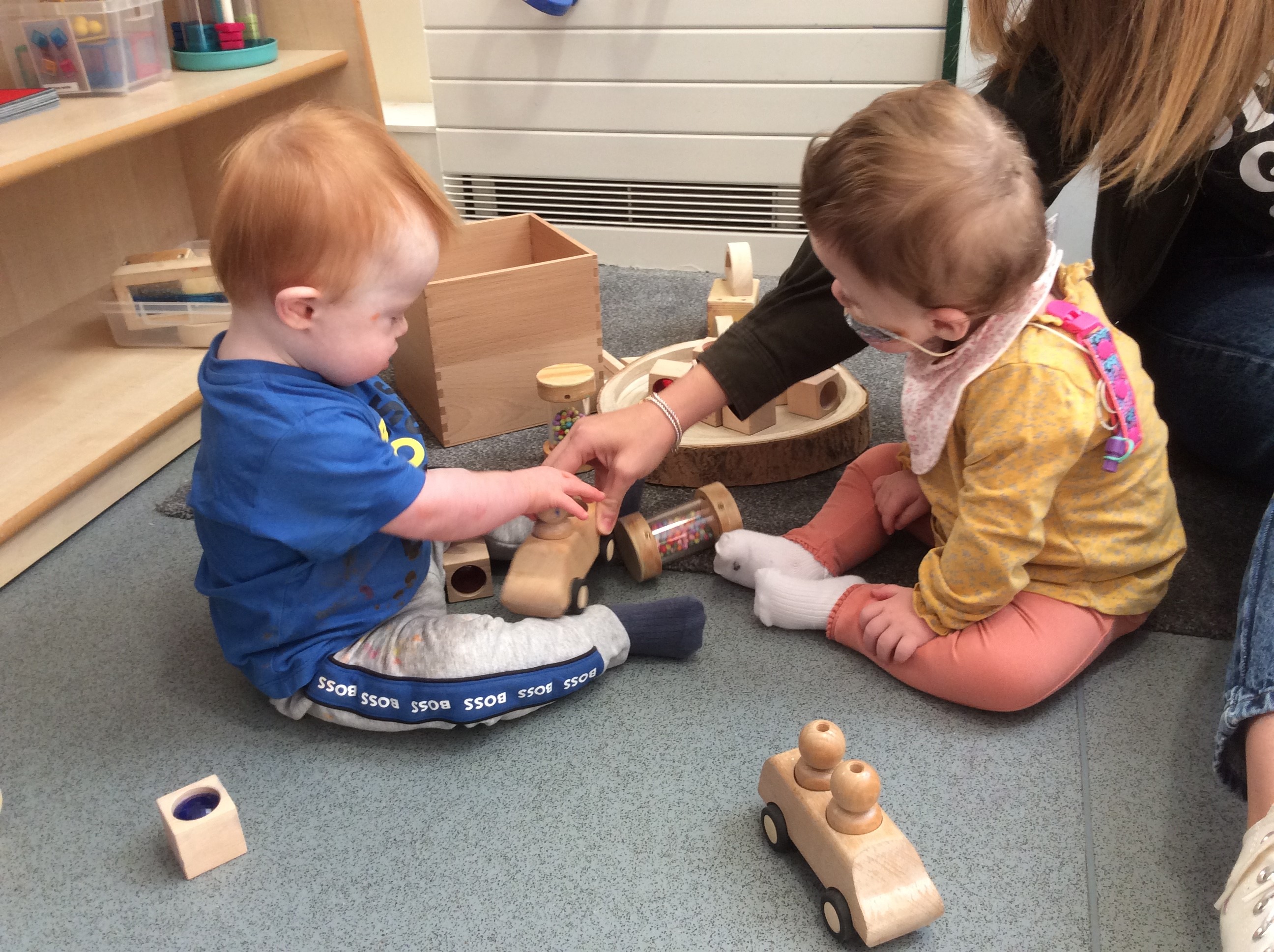Two toddlers playing with wooden toys